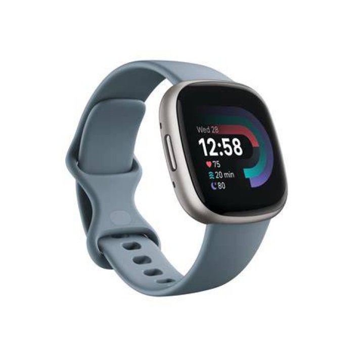 Fitbit Charge 5 Review In Hand with Color A user holds a Fitbit Charge 5 in hand in front of a green concrete wall.