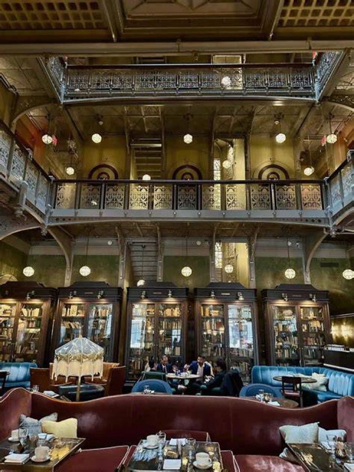 The lobby at The Beekman Hotel, which features green walls, printed rugs, and lots of traditional furniture
